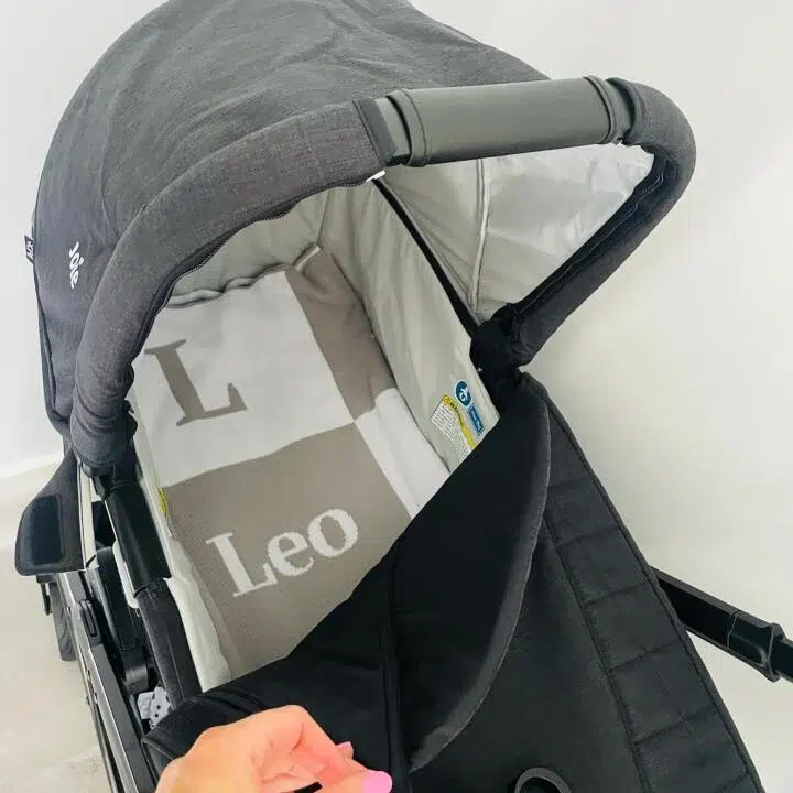 Cobertor de Bebê de Malha com Letra Assinatura em um carrinho